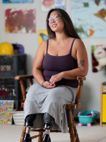 Woman with prosthetic legs smiling while sitting in a colorful room