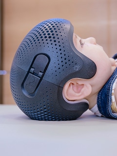Baby wearing a protective helmet lying on a table