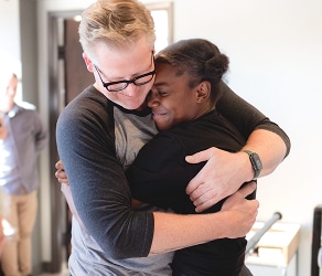 Two people embracing warmly in a bright room