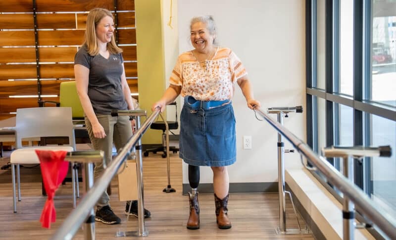 Woman with prosthetic leg doing physical therapy with a therapist in a rehabilitation center