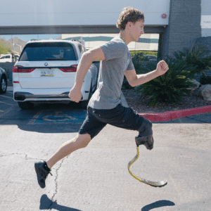 Man running with a prosthetic leg in a parking lot‌, wearing athletic attire.
